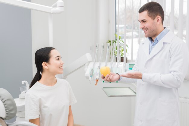 Dentista enseñando manzana a paciente