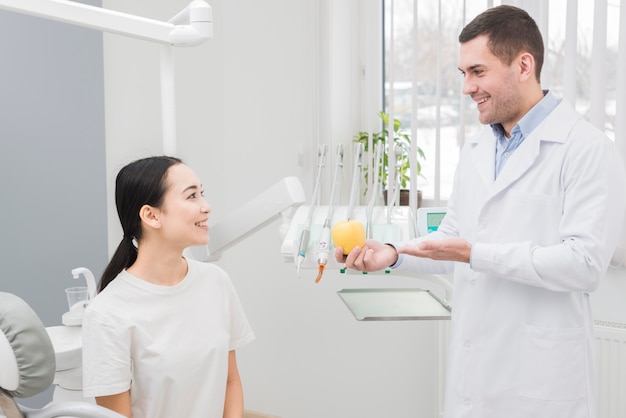 Dentista enseñando manzana a paciente