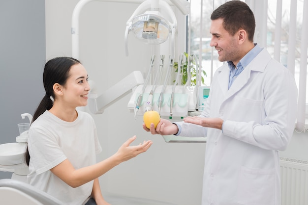 Dentista enseñando manzana a paciente