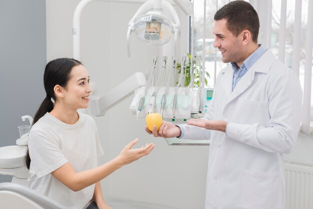 Dentista enseñando manzana a paciente