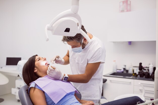 Dentista examinando los dientes del paciente femenino