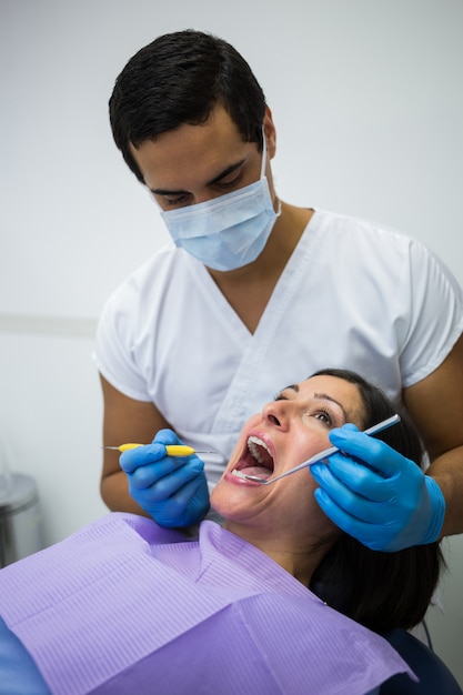 Dentista examinando los dientes del paciente femenino