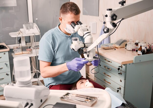 Dentista examinando dientes de pacientes con microscopio de diagnóstico