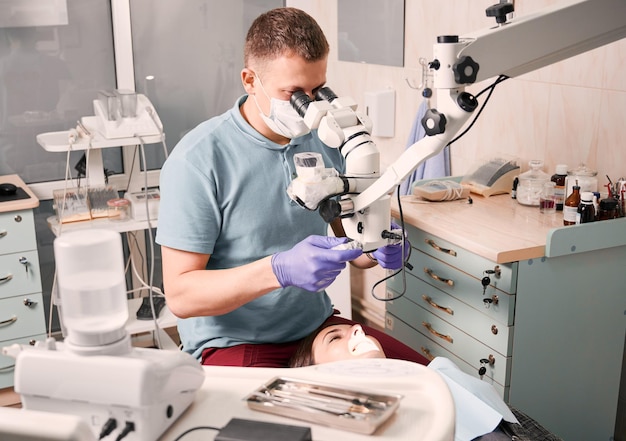 Dentista examinando dientes de pacientes con microscopio de diagnóstico