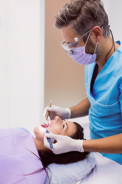 Dentista examinando a una paciente con herramientas