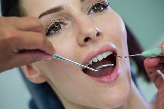 Dentista examinando a una paciente con herramientas