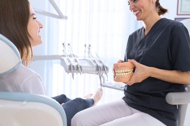 Dentista explicando paciente sobre modelo de dientes en clínica