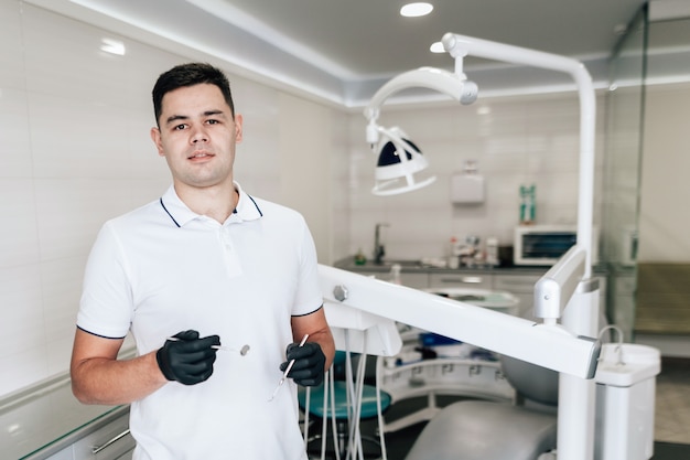 Dentista con guantes quirúrgicos posando en la oficina