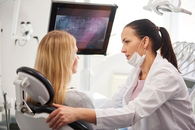 Dentista hablando con mujer preocupada durante el chequeo dental