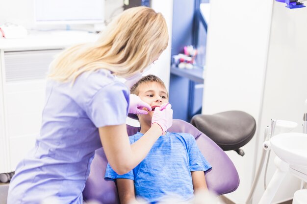 Dentista haciendo tratamiento dental de un niño en clínica.