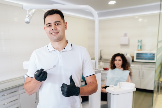 Dentista con instrumento y paciente en la oficina