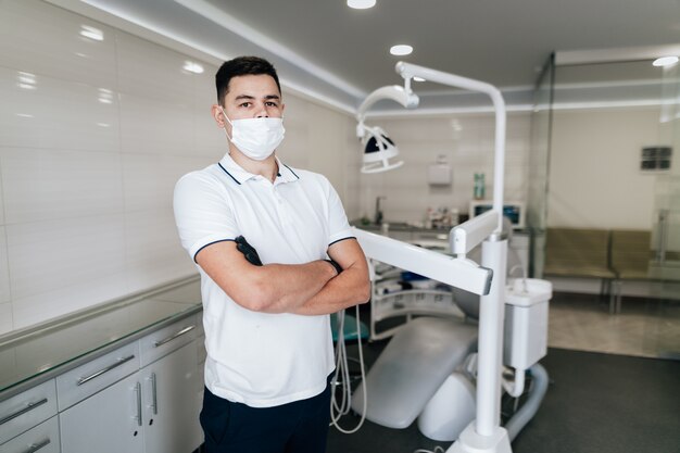 Dentista con mascarilla quirúrgica posando en el consultorio