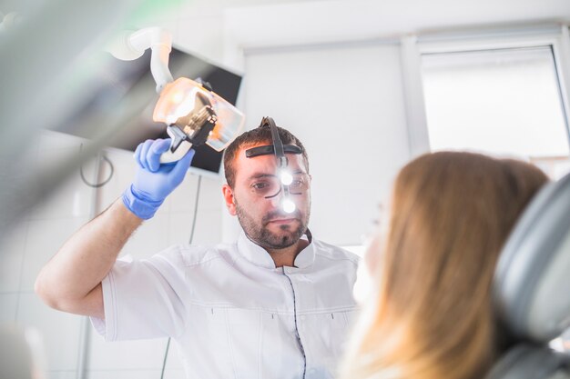 Dentista masculino que examina los dientes de la hembra en clínica