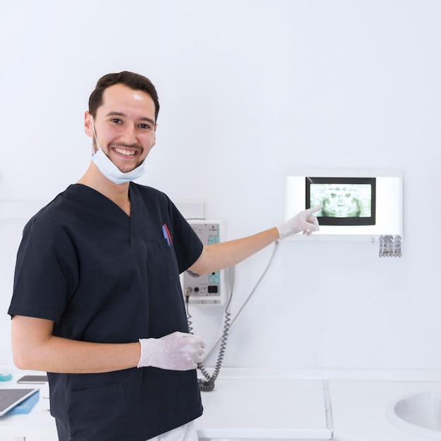 Dentista masculino sonriente que muestra la radiografía dental