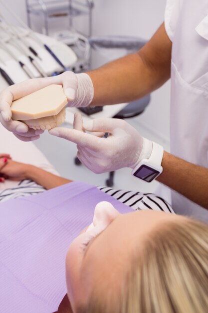 Dentista mostrando modelo de prótesis al paciente