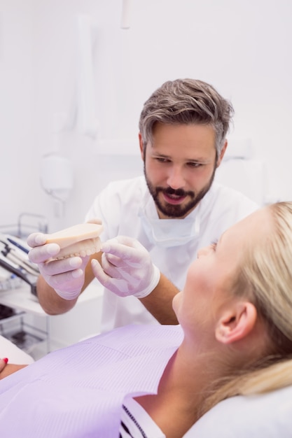 Dentista mostrando modelo de prótesis al paciente