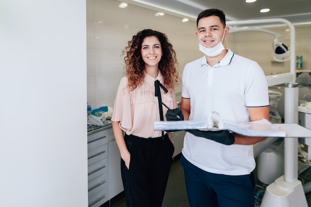 Dentista y paciente sonriendo y posando mientras sostiene una carpeta