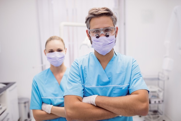 Dentista de pie con los brazos cruzados en la clínica dental