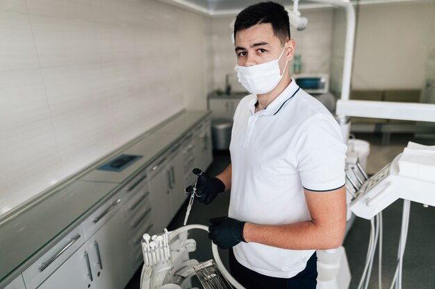 Dentista posando con equipo quirúrgico y mascarilla