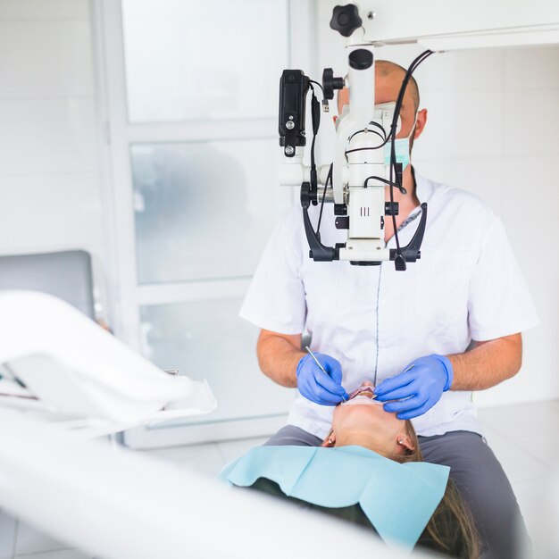 Dentista profesional que examina al paciente con el microscopio dental