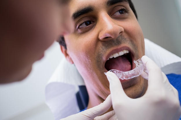 Dentista que ayuda a un paciente a usar aparatos invisibles