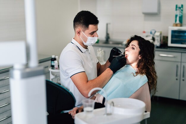 Dentista que controla al paciente en la oficina