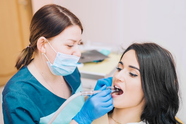 Dentista que cura los dientes del paciente en la clínica