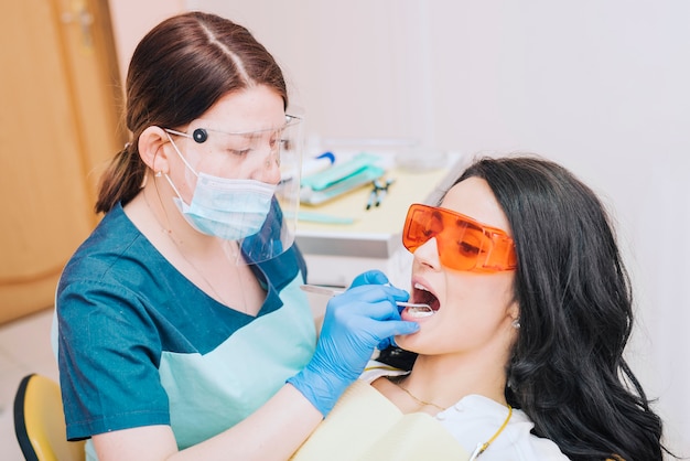 Dentista que examina los dientes del paciente en gafas