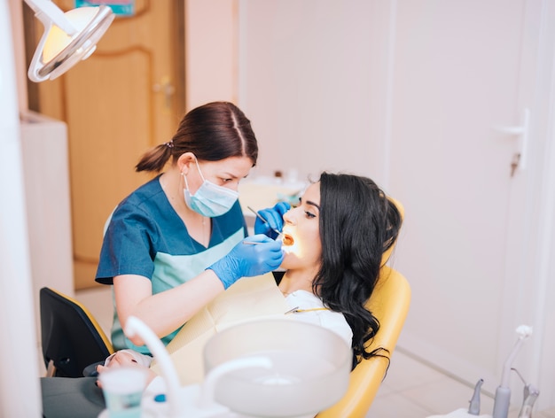 Dentista que examina los dientes de los pacientes en clínica