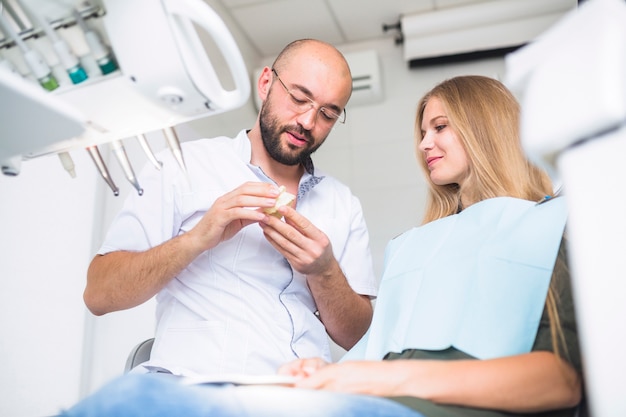 Foto gratuita dentista que explica la higiene dental a paciente femenino