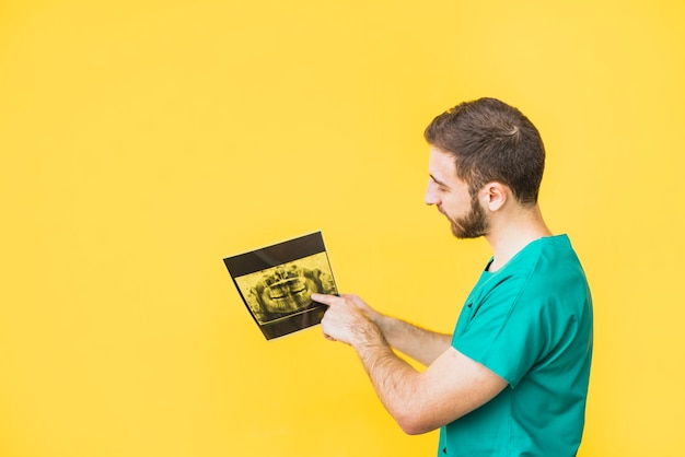 Dentista que señala el dedo a la radiografía de los dientes