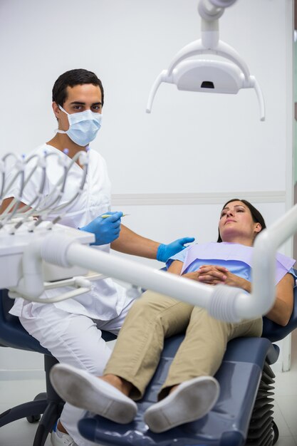 Dentista que trata al paciente femenino en la clínica