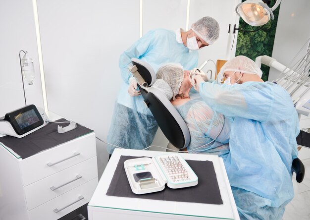 Dentista que usa una máquina de implantes dentales durante el procedimiento de implantología