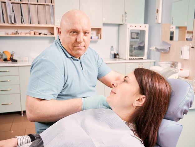 Dentista sentada al lado de una paciente en el consultorio dental
