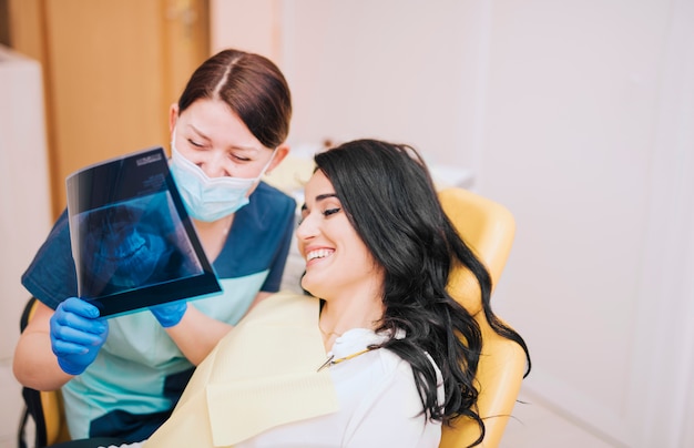 Dentista de sexo femenino que muestra la radiografía de los dientes al paciente