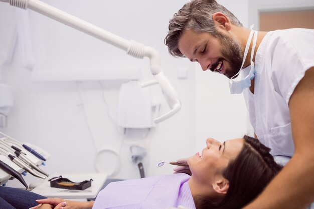 Dentista sonriendo mientras examina al paciente