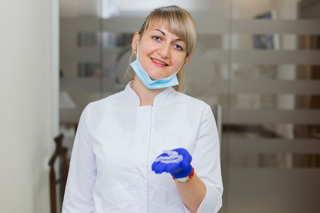 Foto gratuita dentista sonriendo y sosteniendo retenedores invisibles