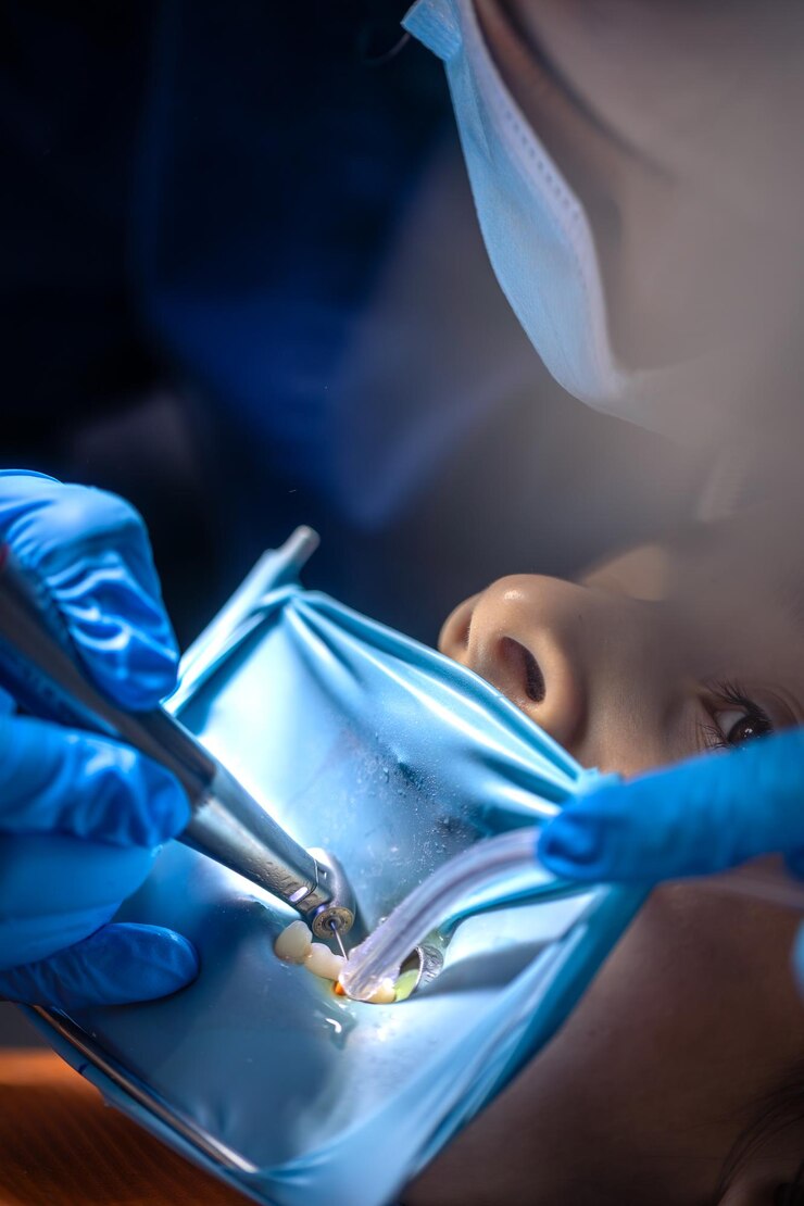 Foto gratuito el dentista trata el diente del niño usando una presa de goma.