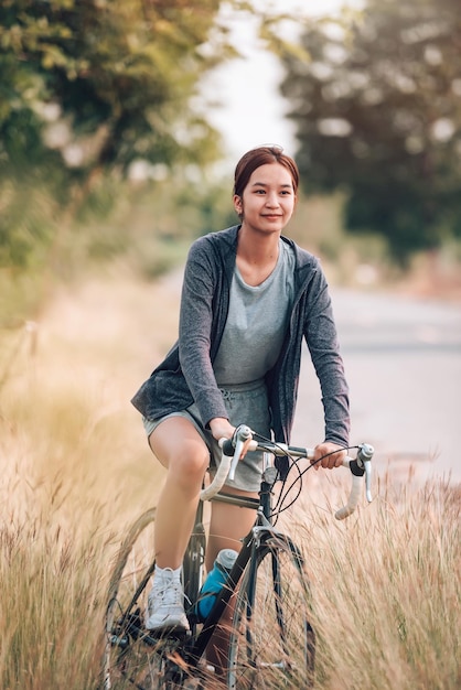 Deporte asiático joven mujer andar en bicicleta para hacer ejercicio y recreación al aire libre en el concepto de transporte freetimeEco