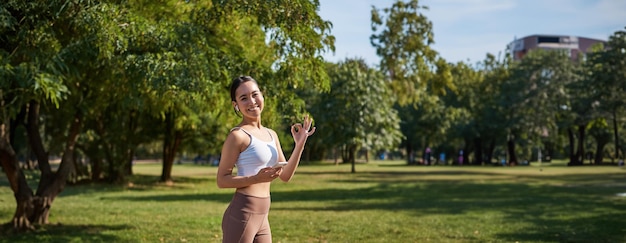 Foto gratuita deporte y bienestar joven deportista en el parque escuchar música y sonreír ejercicio al aire libre trotar en