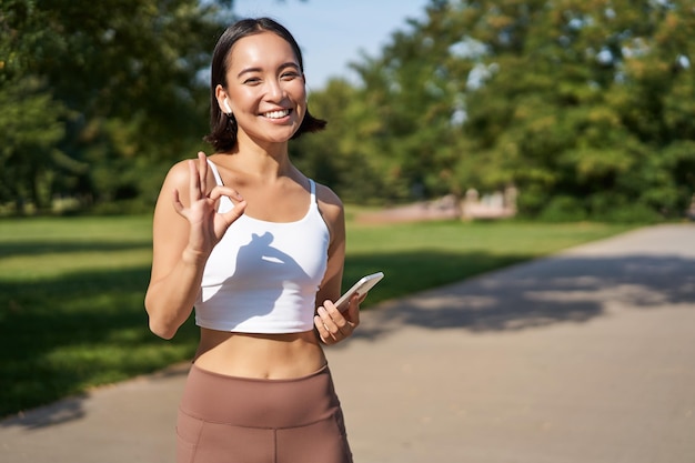 Deporte gente feliz chica asiática deportista mostrando bien signo y sonriente entrenamiento en gimnasio decir sí appro