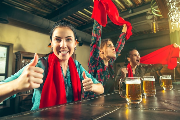 Foto gratuita deporte, gente, ocio, amistad, concepto de entretenimiento: felices fanáticas del fútbol femenino o buenos amigos jóvenes bebiendo cerveza, celebrando la victoria en el bar o pub. concepto de emociones positivas humanas