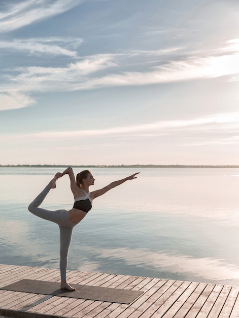 Deportes dama de pie en la playa hacer ejercicios de yoga.