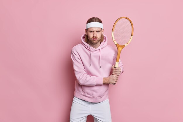El deportista activo serio se coloca con la raqueta de tenis juega el juego favorito entra para el deporte para la salud