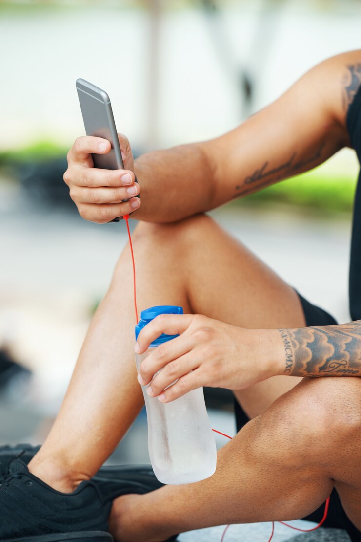 Foto gratuito deportista con agua usando el teléfono