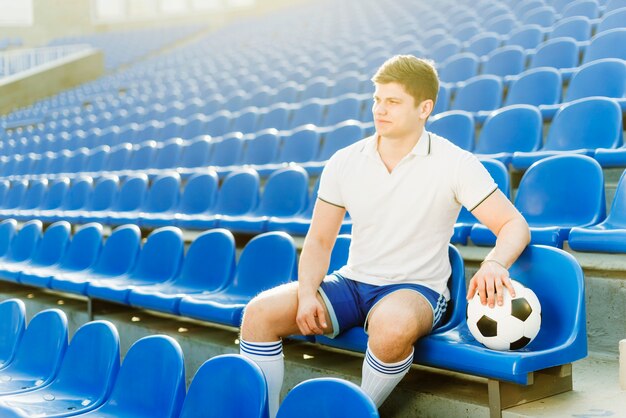 Deportista y balón de fútbol en el estadio