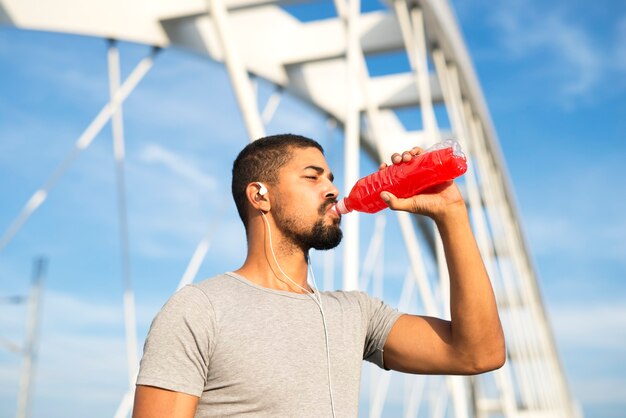 Deportista bebiendo bebida energética refrescante después del entrenamiento hidratando su cuerpo