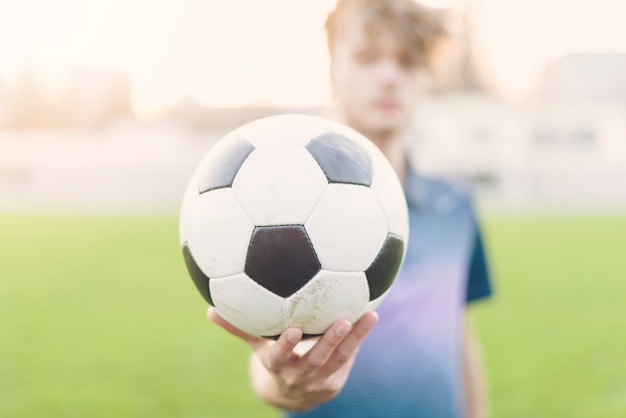 Foto gratuita deportista borrosa mostrando el balón de fútbol