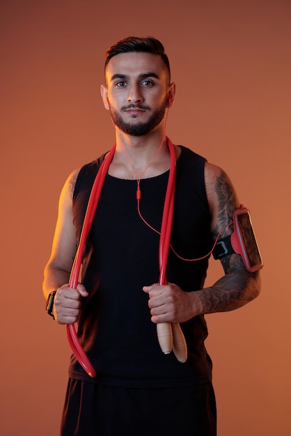 Deportista confiado con auriculares y saltar la cuerda