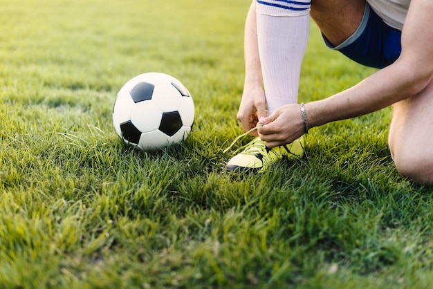 Deportista de la cosecha que ata cordones en campo